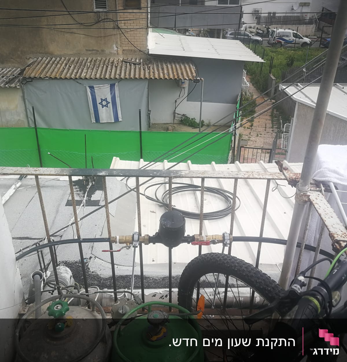 צינור מים כחול מחובר למיכל גז על מרפסת